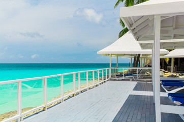 Varadero, Cuba, gorgeous amazing inviting view of a wooden deck with sun sheds near the beach, great view of tranquil turquoise tender ocean and cloudy bluish sky background