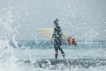 Woman surfer with surfboard going to surf the big waves