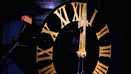 The clock with gilded Roman numerals shows exactly twelve hours. A bells on clock tower beat accurately the midnight. Clock mechanism with the bells.