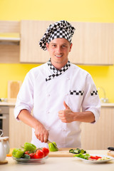 Young professional cook preparing salad at kitchen