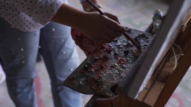 Close up woman mixed paint by brush on the palette slow motion