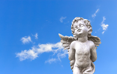Fototapeta premium closeup cupid sculpture on blue sky with soft-focus and over light in the background