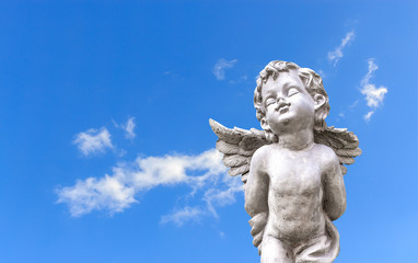 closeup cupid sculpture on blue sky with soft-focus and over light in the background