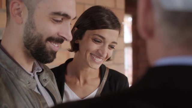 Sales agent talking with clients in new building. Man working as realtor in construction site with customers. Real estate broker showing home to husband and wife. Young couple as buyers of new house