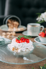 Obraz na płótnie Canvas Pavlova dessert with berries in a beautiful composition. Foodstyling on a wooden background with coffee and strawberries.