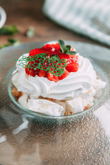 Pavlova dessert with berries in a beautiful composition. Foodstyling on a wooden background with coffee and strawberries.
