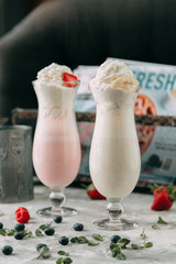 Milkshakes with blueberries and raspberries. Food styling with decor on a wooden background.