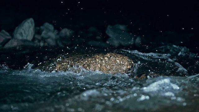 Slow motion of waves on dark water surface with play of flecks of bright light close up. Amazing dramatic natural background. Shooting with 180fps. Epic mystical and magic night view. Crystal clear