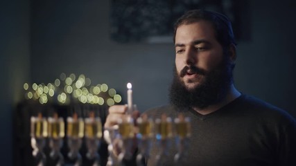 orthodox jewish person light a hanukkah menorah with olive oil candles.