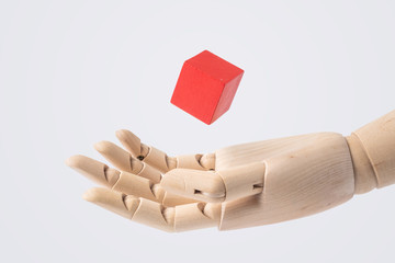 wooden hand with red cube isolated on white