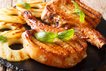 Grilled pork chop with pineapple and basil close-up on slate. horizontal