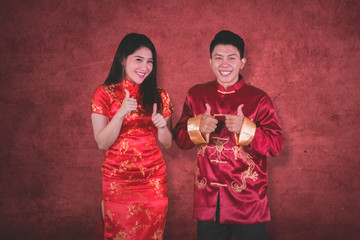 Obraz premium Asian couple shows thumbs up on studio