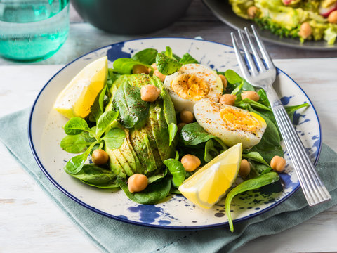 Avocado spinach salad with chickpeas and hard boiled eggs served on a dish. Fats and proteins