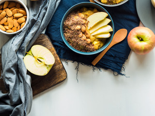 Cozy morning concept with turmeric amaranth porridge served with apples, flax seeds and almonds. Healthy plant based vegan breakfast. Flat lay