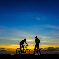 Fototapeta premium Cyclists with bicycles at the beach, at dusk.