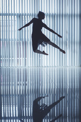 Beautiful ballerina jumping near the window