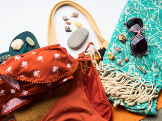 Fototapeta premium Beach female fashion accessories swimsuit, sun glasses, hat, flip flops, towel and bag. Summer traveling holiday concept flat lay
