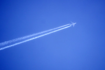 plane with condensation trail in front of blue sky .