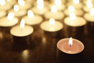 Tea light candles burning in darkness. Advent or memorial prayer candle flame.