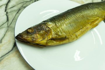 Hot smoked herring on plate isolated on a white background .