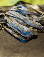 Homemade piles of fresh black fettuccine pasta that powdering flour to keep them from sticking.