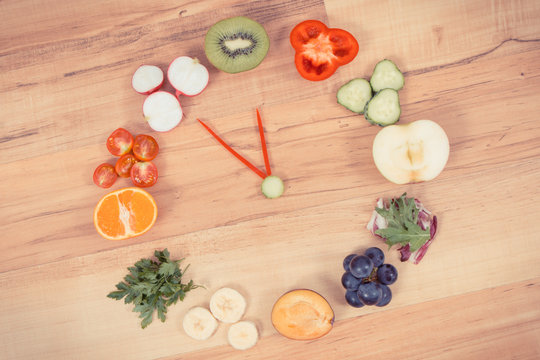 Fruits and vegetables in shape of clock showing time for healthy eating containing vitamins