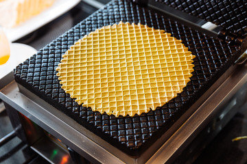 Crispy thin waffle bowl inside iron machine.