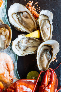 Boiled lobster, fresh oysters, shrimps, mussels and clams served in black stone plate.