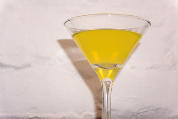 Yellow cocktail in martini glass isolated on a white background .