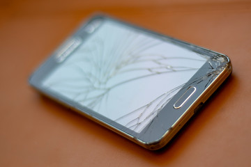 Broken screen mobile phone on orange background