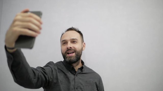A man with a beard makes a selfie on the phone