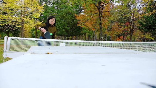 A Happy Woman Playing Table Tennis or Ping Pong in Park, Fall and Autumn Season