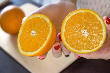 young woman holding halves of an orange