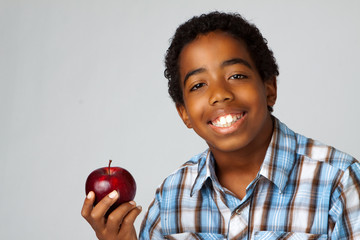 Young African American kid eating an apple isolated on white.