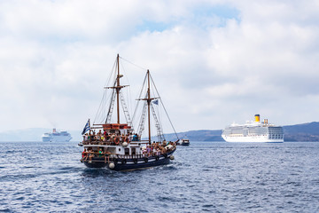 Obraz premium An old ship next to several large cruise ships near the port of Fira, Santorini, Greece