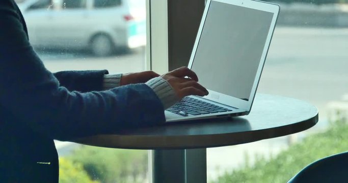 4k silhouette of female working on laptop computer in coffee shop desk,city pedestrian and traffic window view,business correspondence using a laptop,keyboard input,write article,writing report.