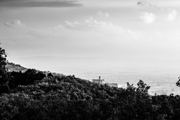 Beautiful view of Assisi town (Umbria) in autumn from an unusual place, behind an hill with trees