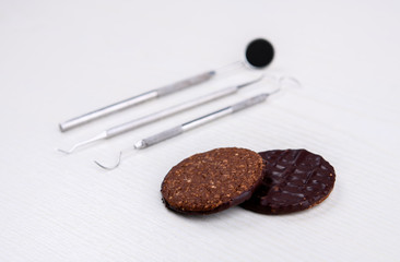 dental instruments on and chocolate cookie bright ground