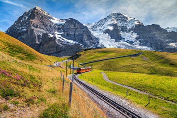 Electric tourist train and high snowy mountains with glaciers, Switzerland