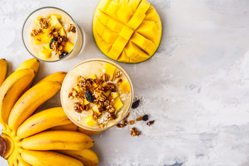 Mango banana smoothie with granola and coconut in a jar, top view.