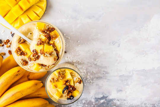 Mango Banana Smoothie With Granola And Coconut In A Jar, Top View.