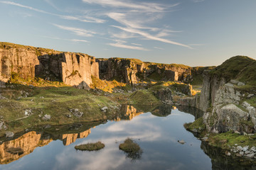 Stunning landscape sunset image over abandoned Foggintor Quarry in Dartmoor with raking soft...