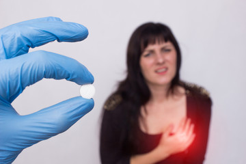 Doctor holds pill in hand from cardiovascular system, patient girl stands in the background and holds on to heart, heart problems, medical