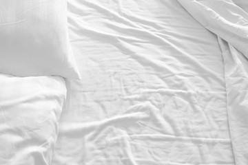 white pillow with messy messy blanket on bed in bedroom Close up of bedding sheets with copy space.