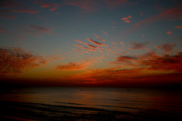 Fototapeta na wymiar sunset at sea, red sun sits behind the horizon