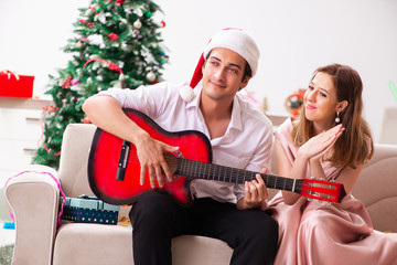 Young couple playing guitar at christmas