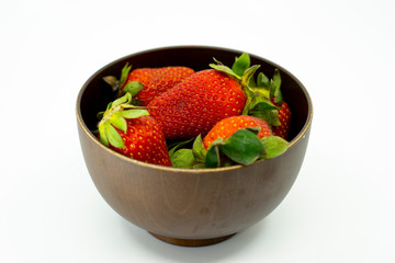 Strawberry in a wooden bowl isolated on white background.