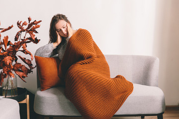 Tired young woman lying on the sofa on white wall background. Headache. Girl holding head