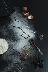 Constellations formed on a dark background with a twist of flour, cooking cupcakes and star cookies with black pepper