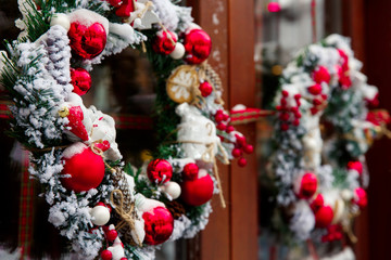 Christmas wreath on a door with red decoration, balls and snow